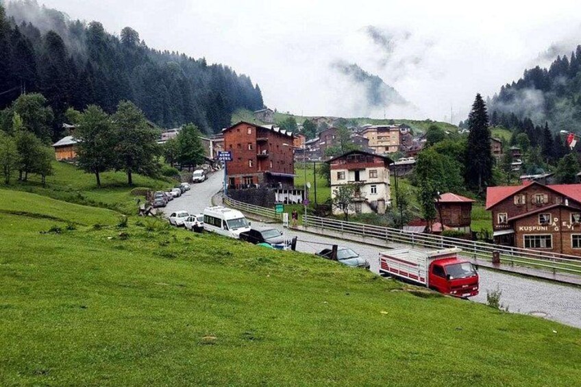 A mountainous village with a red bus, buildings, and a road. 4