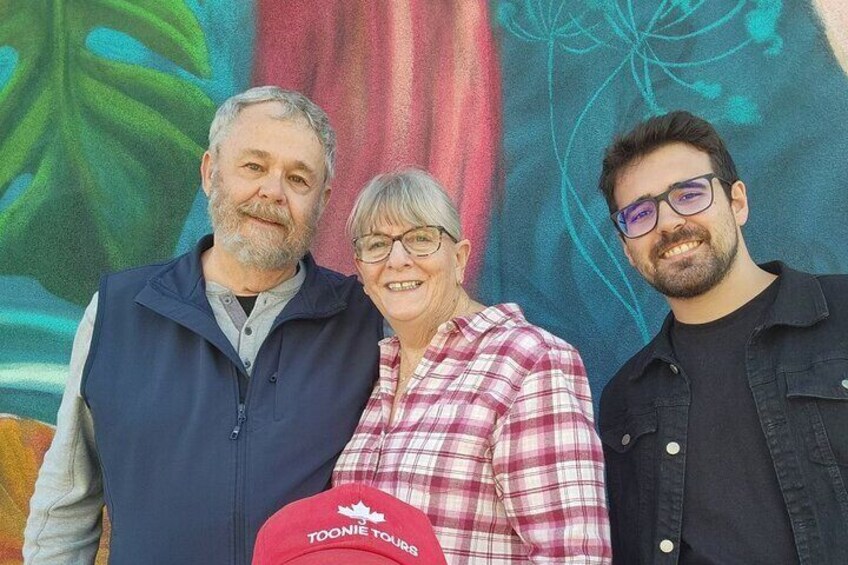 Three people standing in front of a colorful mural. 5