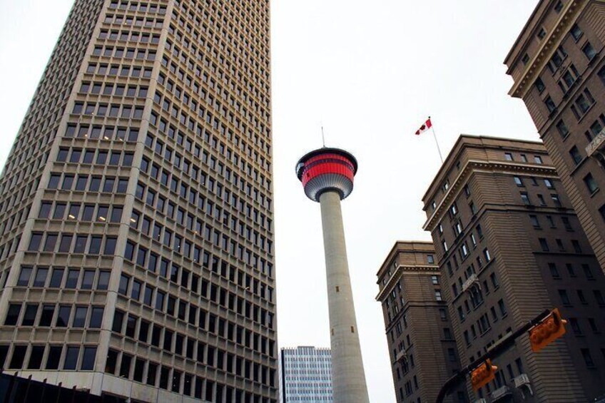 A tall building with a tower, a flag, and another building in the foreground. 2
