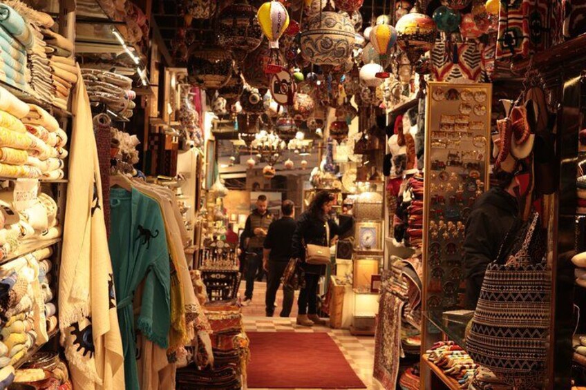 Un étroit couloir d’un marché, bordé de différents étals vendant des textiles et des articles de décoration. 2