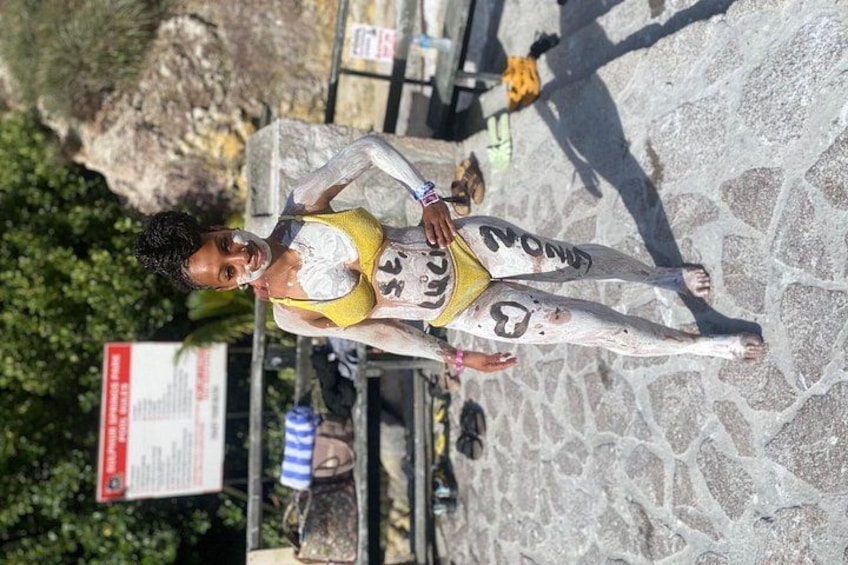Una persona con vernice bianca addosso, in piedi su una superficie di pietra, con un cartello sullo sfondo. 3