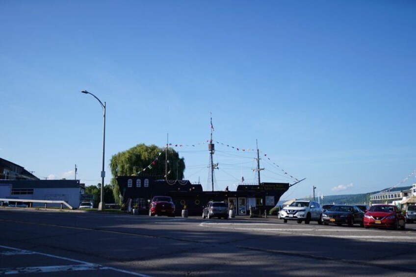 A coastal road with parked cars, a building with a flag, and a clear blue sky. 5