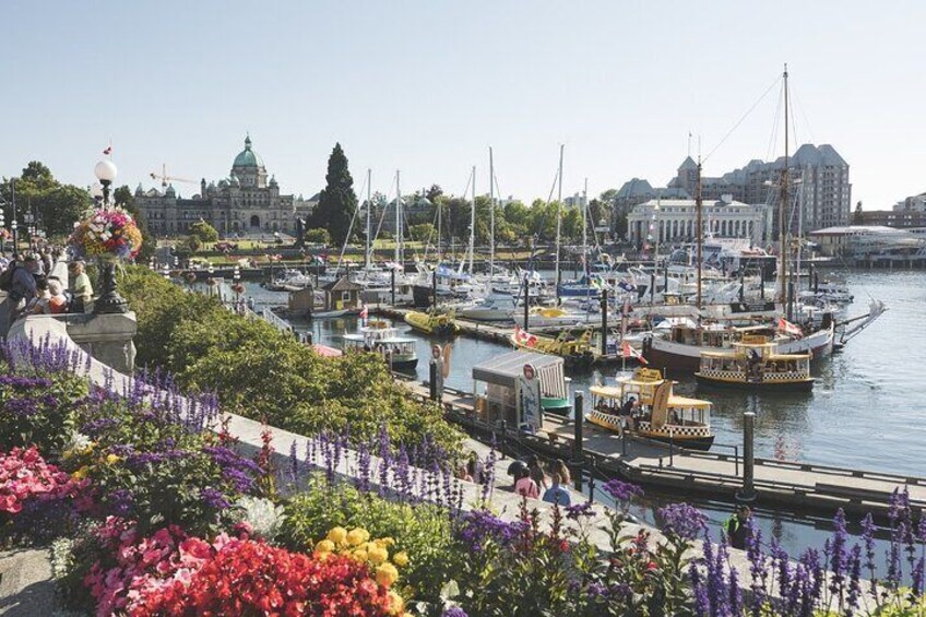 A harbor with boats, a flower-adorned walkway, and a prominent building with a green dome. 1