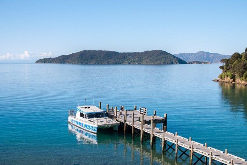 A boat docked at a pier with calm water and a hilly landscape in the background. 2