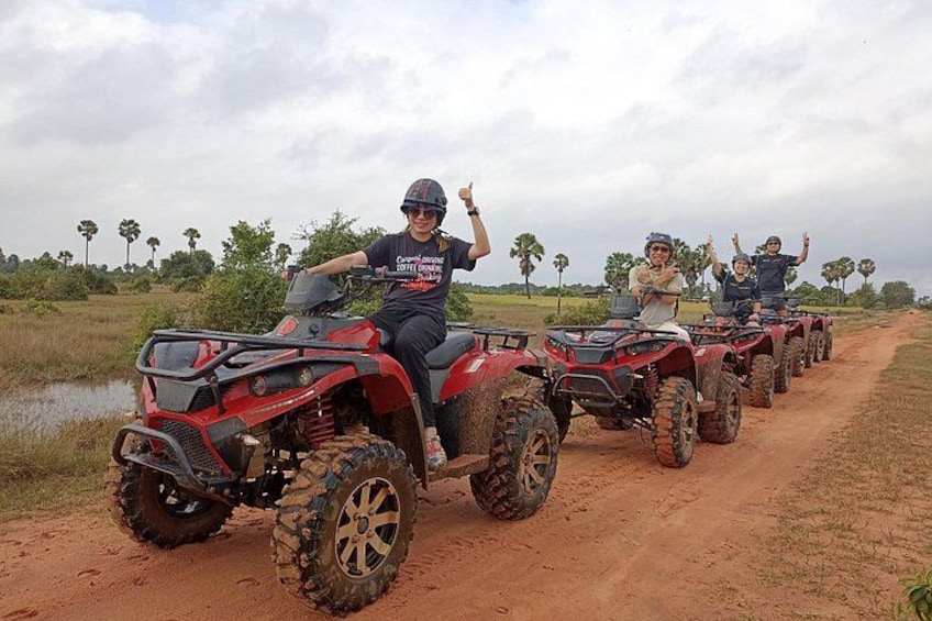 Un groupe de personnes conduisant des quads sur un chemin de terre, avec de l’eau et des arbres en arrière-plan. 5