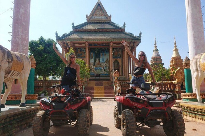 Deux personnes sur des quads devant un temple orné d’une fresque murale. 3