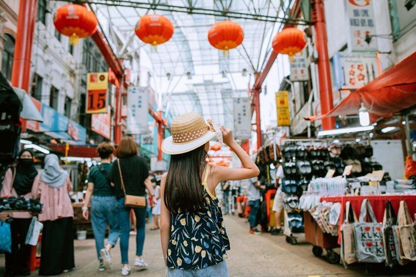A bustling indoor market with red lanterns, various stalls, and shoppers. 2
