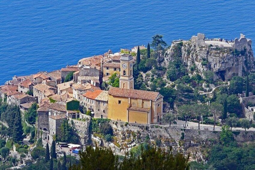 A coastal town with historic buildings, a prominent clock tower, and a castle on a cliff. 1