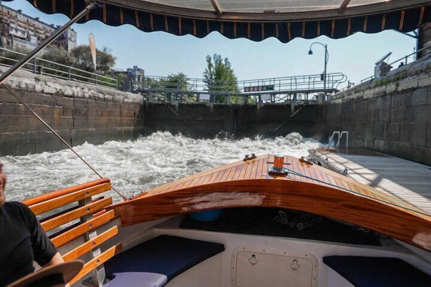 A wooden boat navigating through a canal with water flowing rapidly. 5