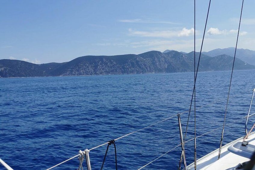 Un velero en un mar tranquilo con montañas al fondo. 1