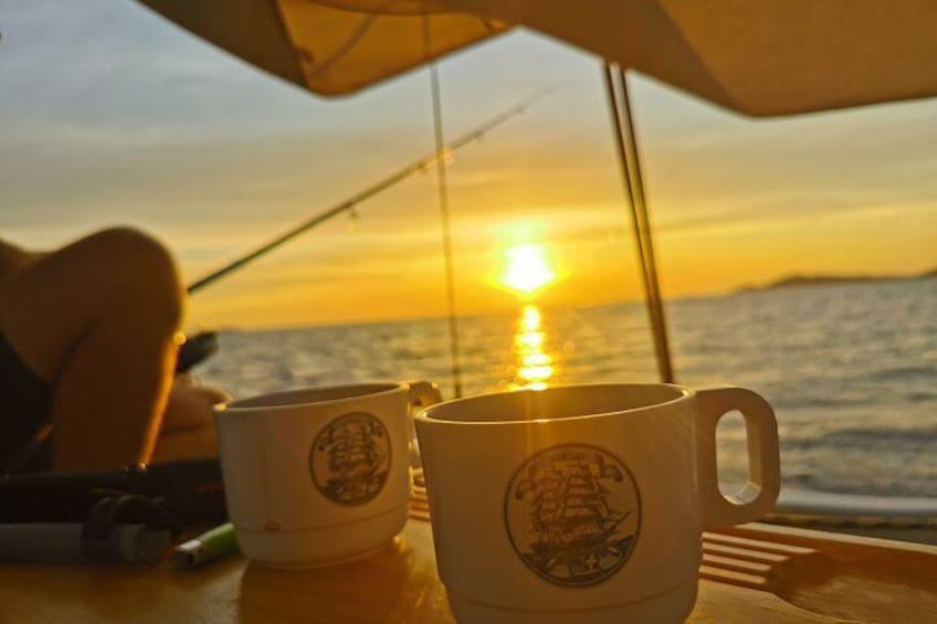 Dos tazas de café con un logotipo, una persona pescando y una puesta de sol sobre el océano. 3