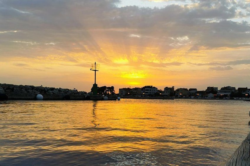 Un atardecer sobre una masa de agua con un faro y edificios al fondo. 4