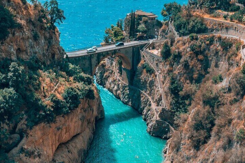 Un puente sobre un río turquesa, rodeado de acantilados rocosos y vegetación escasa. 1