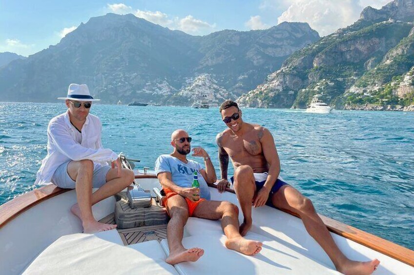 Tres personas en un bote en un cuerpo de agua, con montañas al fondo. 5