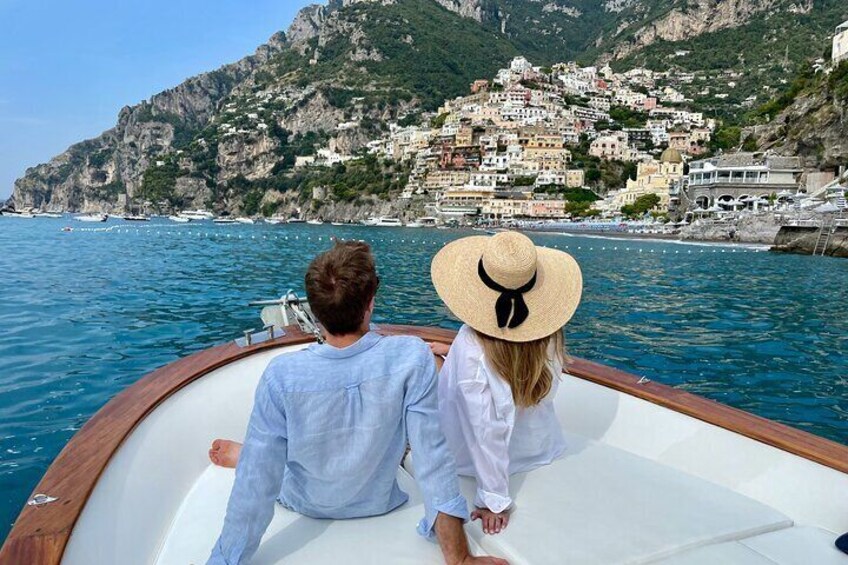 Dos personas en un bote con un pueblo costero al fondo. 3