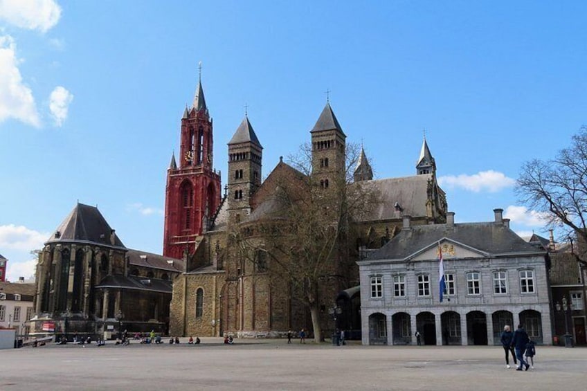 Un complejo histórico de edificios con una torre roja destacada, una iglesia y un edificio blanco con ventanas de arco. 4
