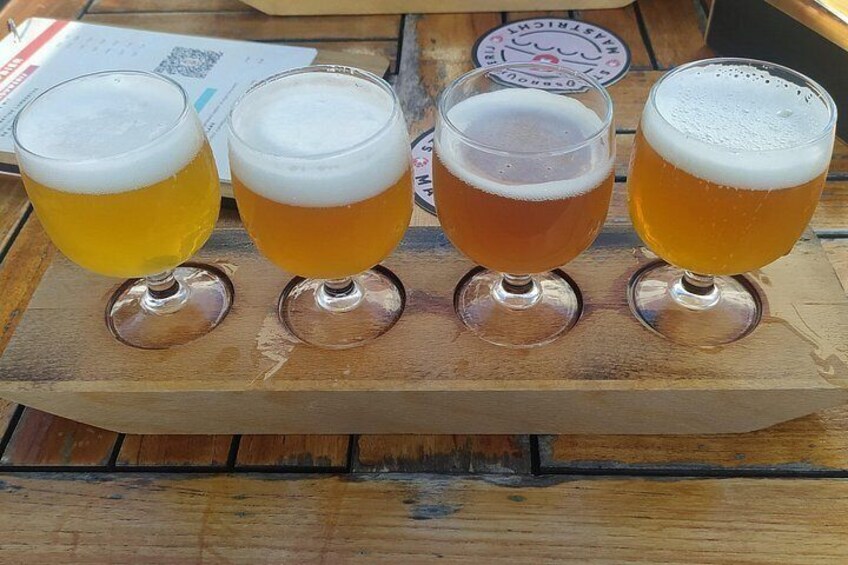 Cuatro vasos de cerveza sobre una bandeja de madera. 2