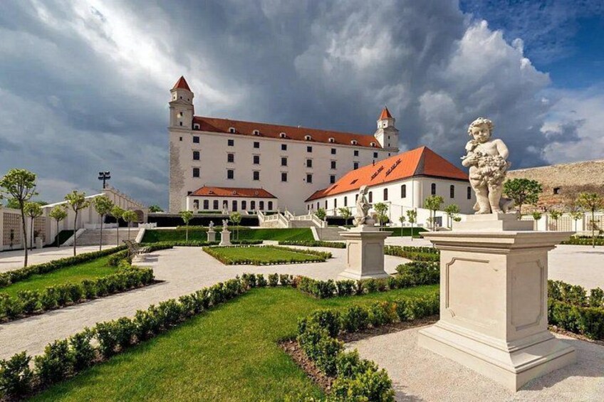 A castle with a red roof, a tower, and a statue of a cherub in a garden. 3