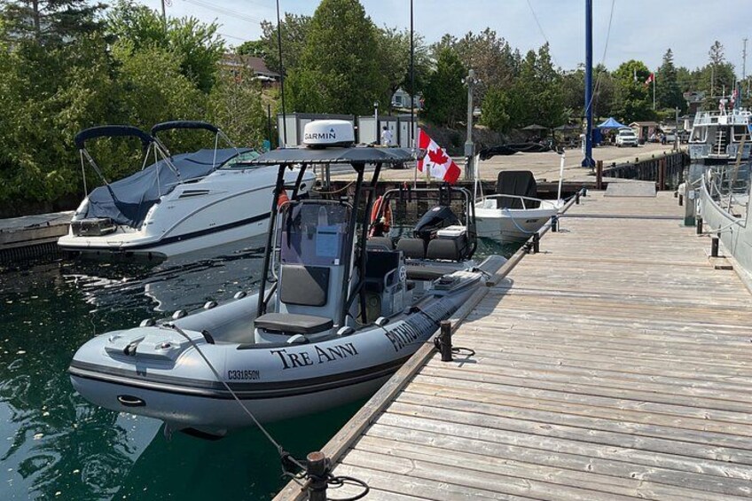 Un barco llamado 'TRE ANNI' amarrado en un muelle de madera con otros barcos y una bandera canadiense. 2