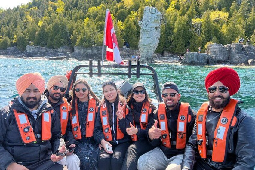 Un grupo de personas en un bote, usando chalecos salvavidas y con una bandera. 3