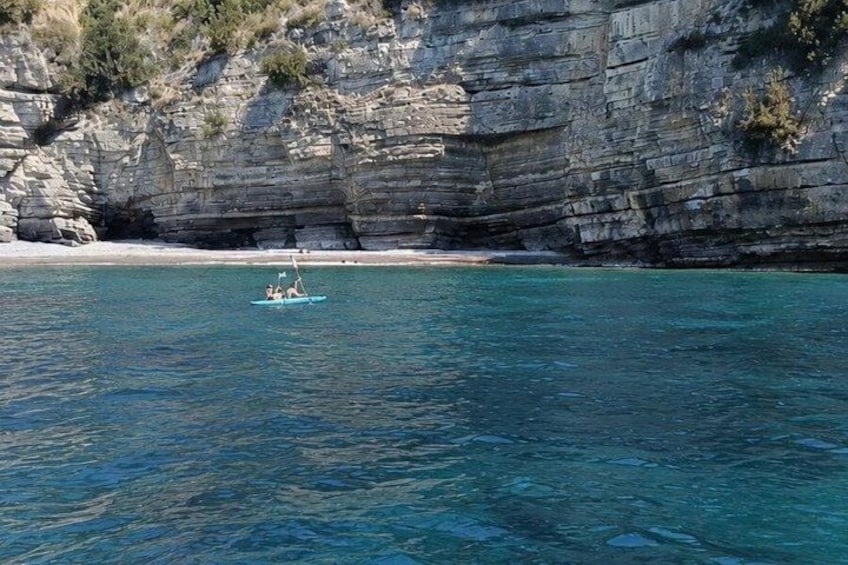 Un bateau sur une eau turquoise et calme, avec une falaise rocheuse en arrière-plan. 3