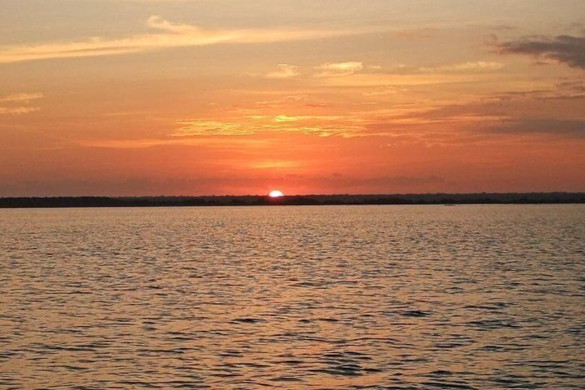 A sunset over a calm body of water with a visible horizon line. 3