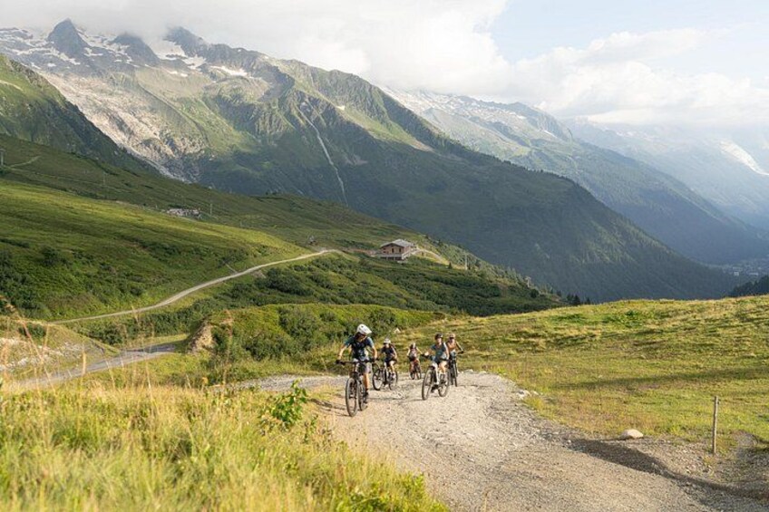 Un groupe de cyclistes sur un chemin de gravier, entouré de collines verdoyantes et de montagnes. 5