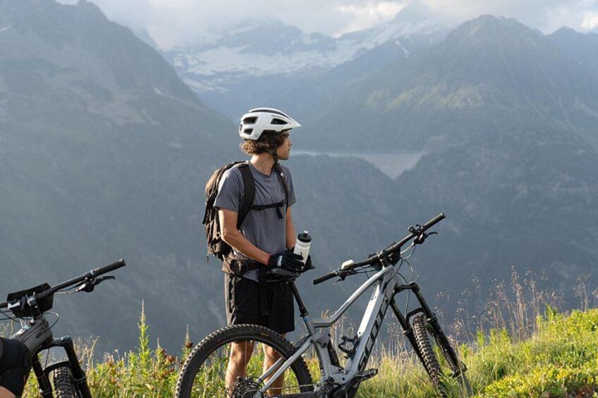 Une personne se tient debout sur une montagne, avec un vélo et un sac à dos. 3
