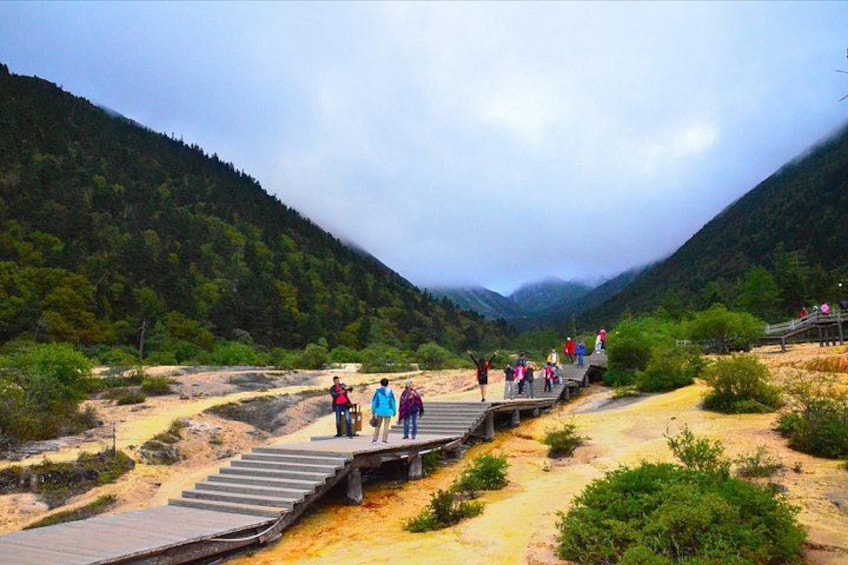 A wooden bridge over a river with people walking on it. 2