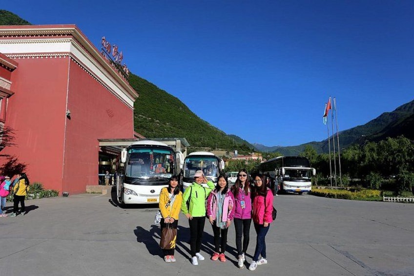 A group of people standing in front of buses with a mountainous landscape in the background. 3