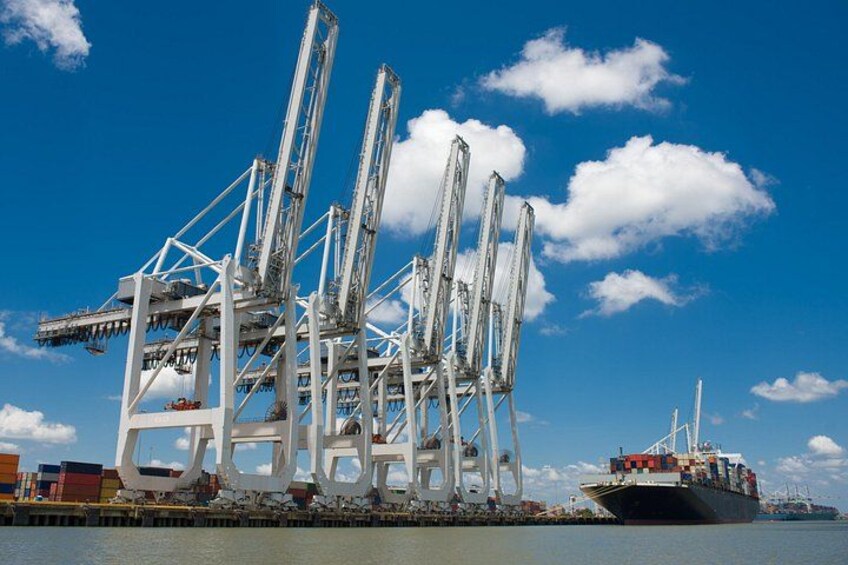 A cargo ship docked at a port with large cranes and containers. 3