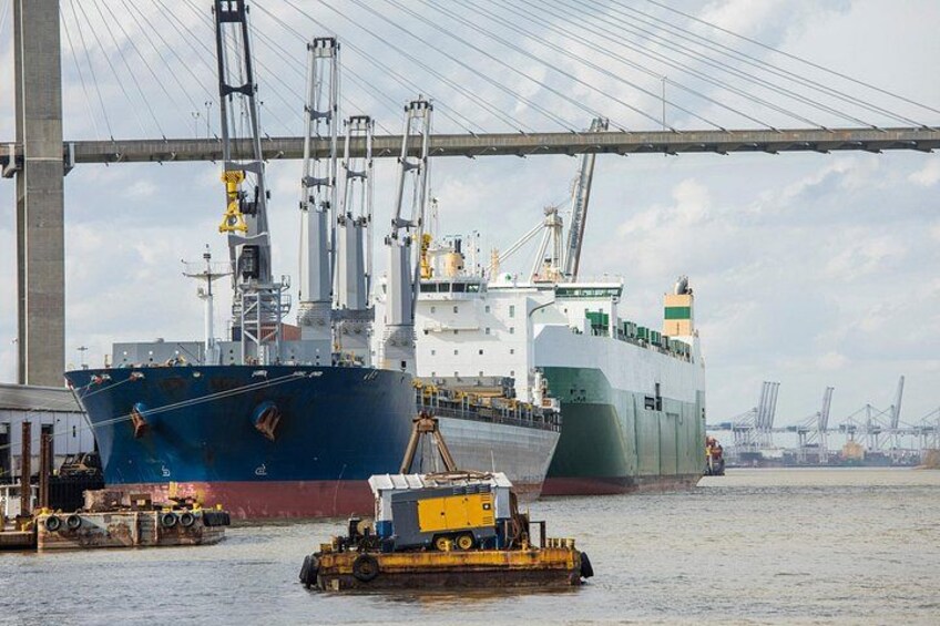 A large cargo ship docked at a port with cranes and a tugboat nearby. 5