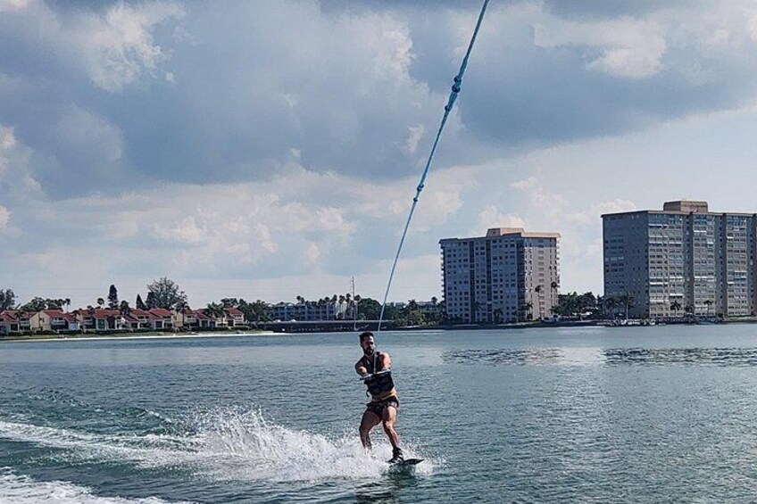 Une personne fait du wakeboard sur une étendue d’eau, avec des bâtiments en arrière-plan. 5