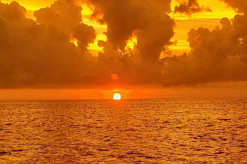 A sunset over a body of water with clouds reflecting the orange sky. 2