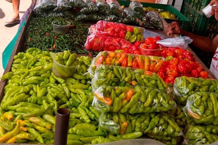 A market stall with green and red peppers, some wrapped in plastic. 4