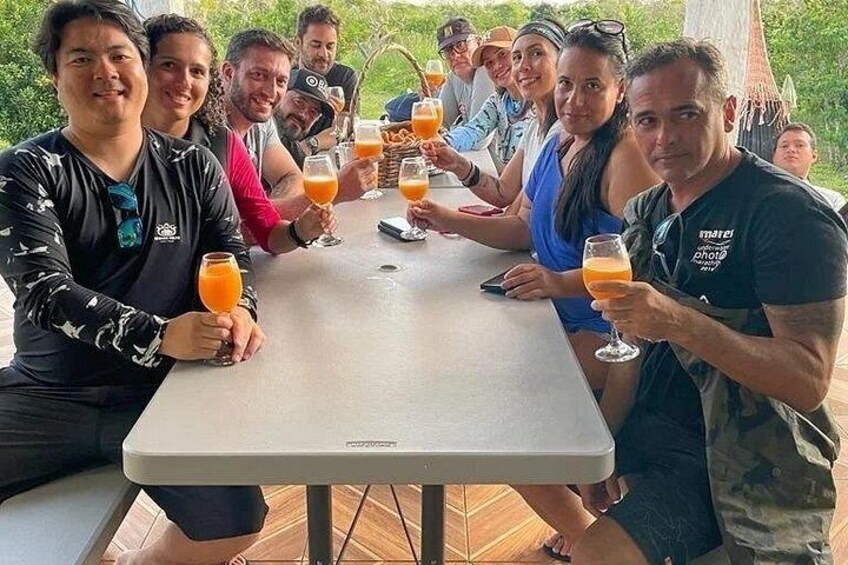 A group of people sitting at a table outdoors, holding drinks. 2