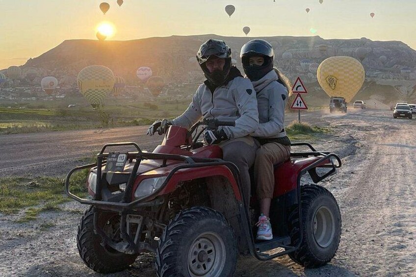 Et par køre på en ATV på en grusvej med luftballoner i baggrunden. 4