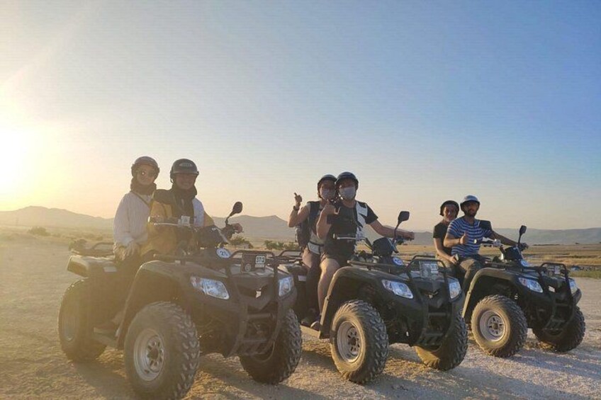 Four people on ATVs in a desert landscape with mountains in the background. 1