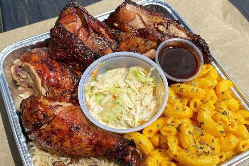 A tray with grilled meats, coleslaw, macaroni, and two dipping sauces. 1