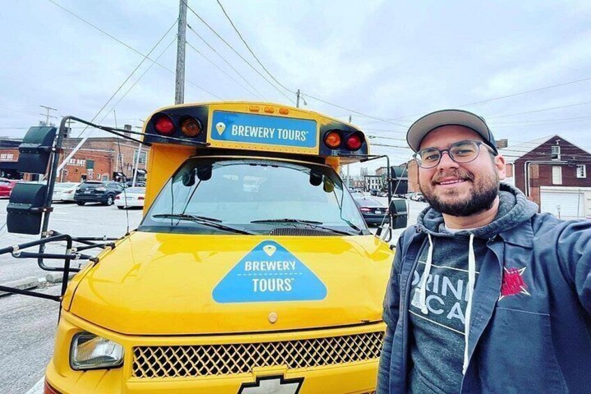 En gul buss med texten ”BRYGGERIBESÖK” på sidan står parkerad på en gata med byggnader i bakgrunden. 2