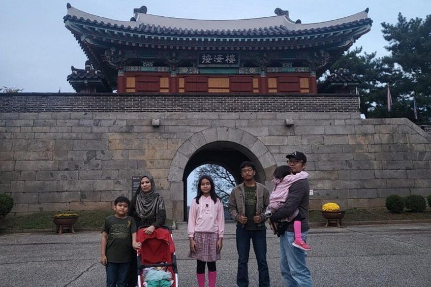 A traditional Korean gate with a family in front. 2