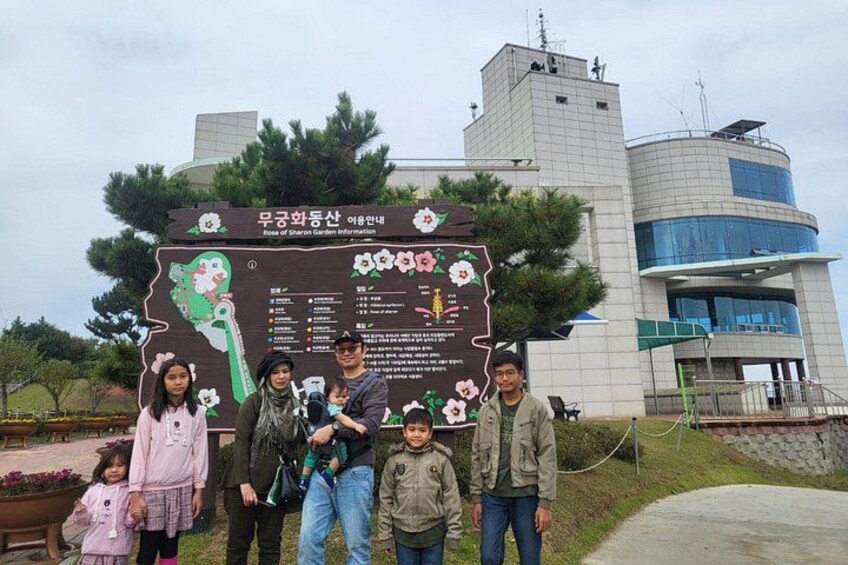 A group of people standing in front of a signboard with information about a garden. 3