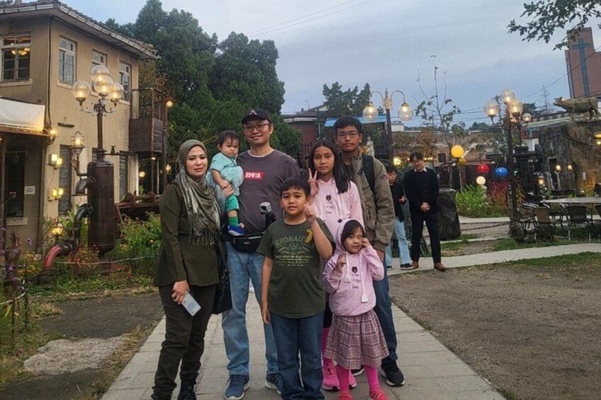 A group of people standing in a public square with a building and street lamps in the background. 4