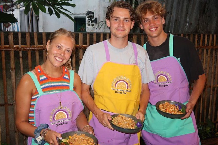 Three people wearing aprons with logos, holding bowls of food. 2