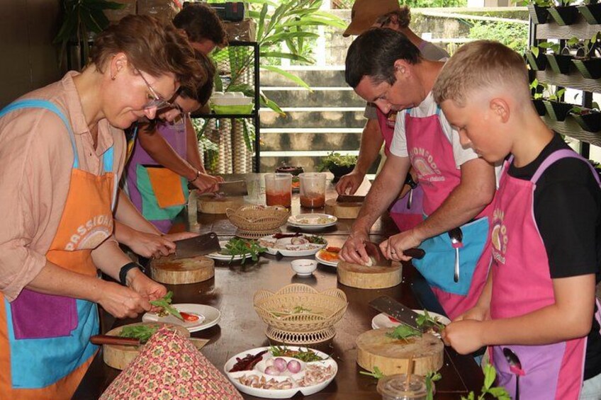 People preparing food at a table with various ingredients and tools. 2