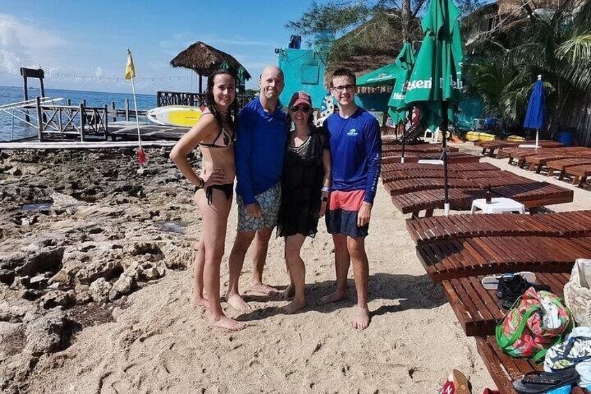 Una spiaggia con sedie a sdraio di legno, una tavola da surf e una torretta di salvataggio sullo sfondo. 3