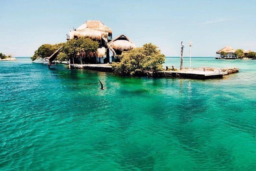 A tropical island with thatched-roof buildings and clear turquoise waters. 4