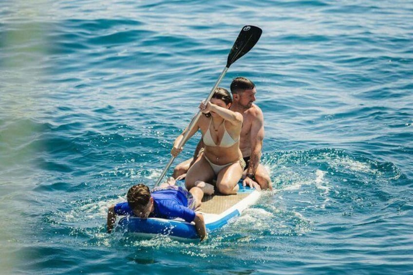 Två personer på en liten uppblåsbar flotte ute på havet, där den ena personen paddlar. 2