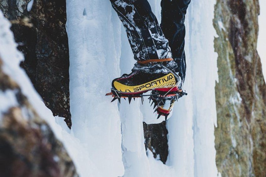 En person som klättrar på ett snöigt berg och bär en gul och svart känga med texten ”SPORTIVA”. 5