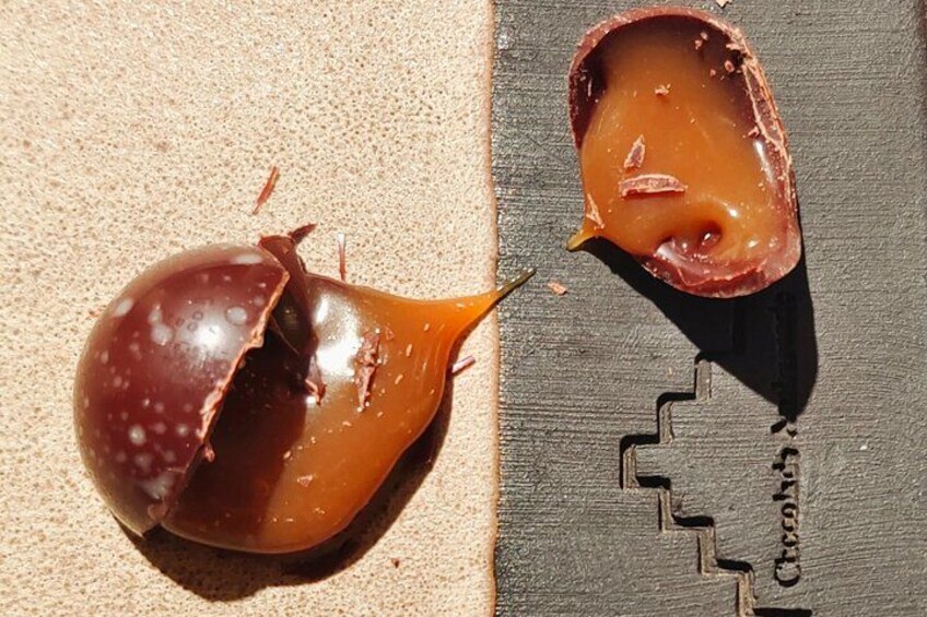 Une coque en chocolat, dont on a croqué un morceau, révélant un cœur de caramel onctueux. 2